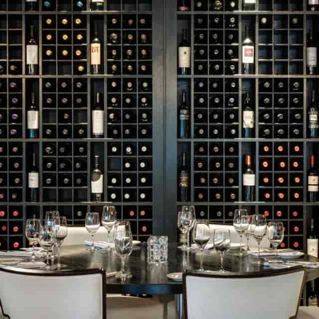 Semi-private dining room with wine cellar backdrop for upscale events and fine dining.