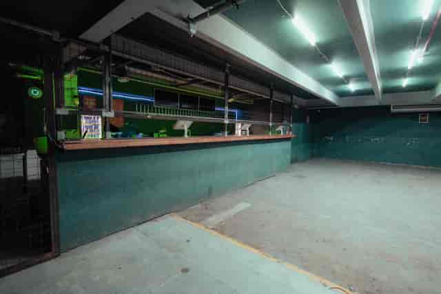 Spacious industrial venue with green lighting, ideal for creative events and gatherings.