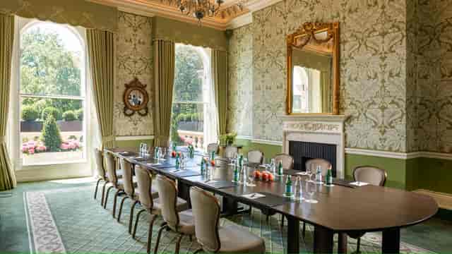 Sophisticated meeting room with lush green walls, perfect for corporate events.