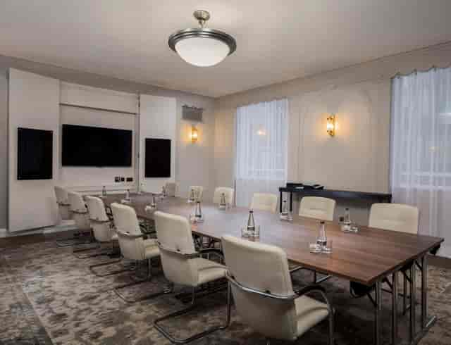 Meeting room at The Bottom Line, Queens Hotel, with polished table and modern tech.