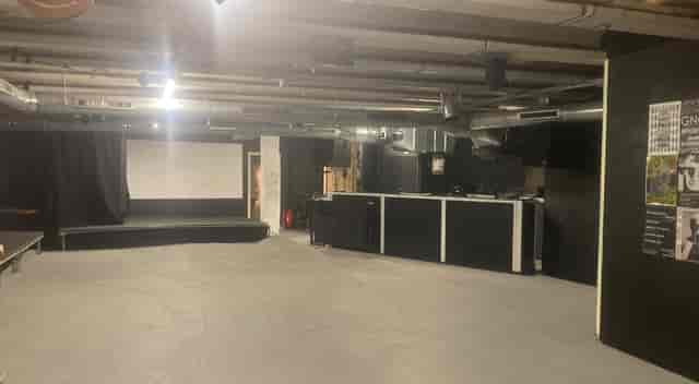 Versatile minimalist event space with stage and bar for meetings and workshops.