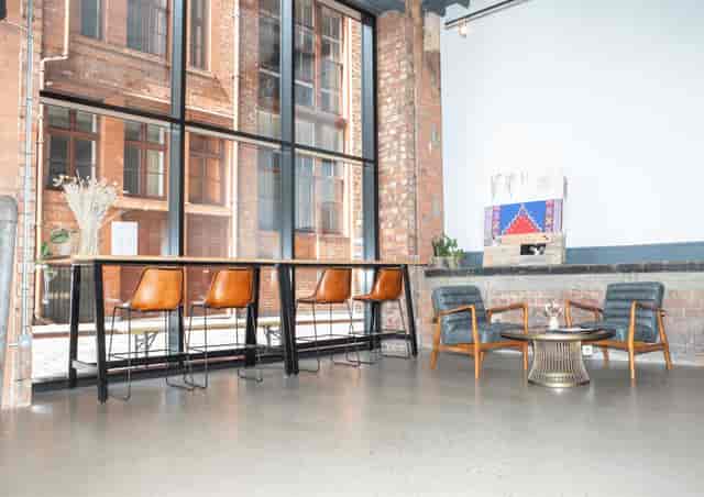 Modern industrial meeting space with large windows, ideal for networking and gatherings.