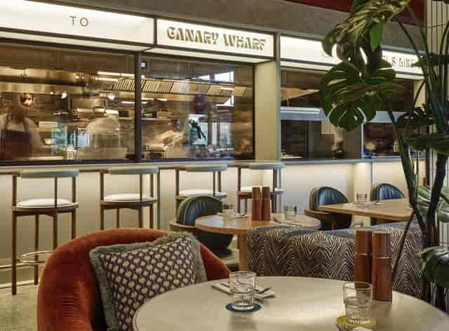 Modern dining space with open kitchen, perfect for casual meetings and upscale events.