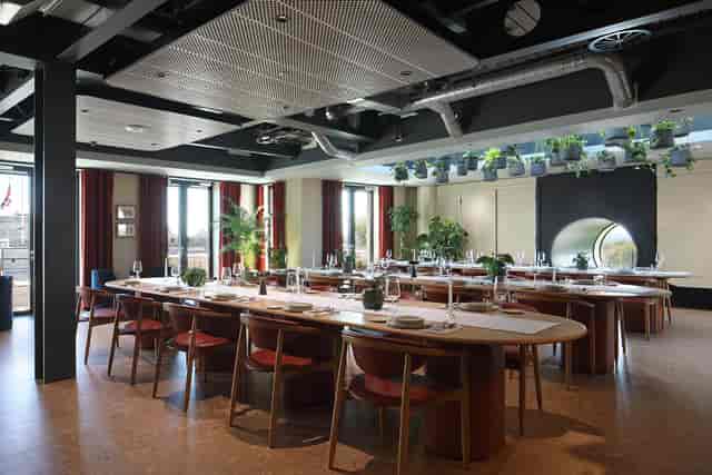 Modern event space with long tables and greenery for meetings and gatherings.