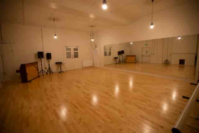 Versatile event space with polished wooden floors and large mirror for workshops or dance classes.
