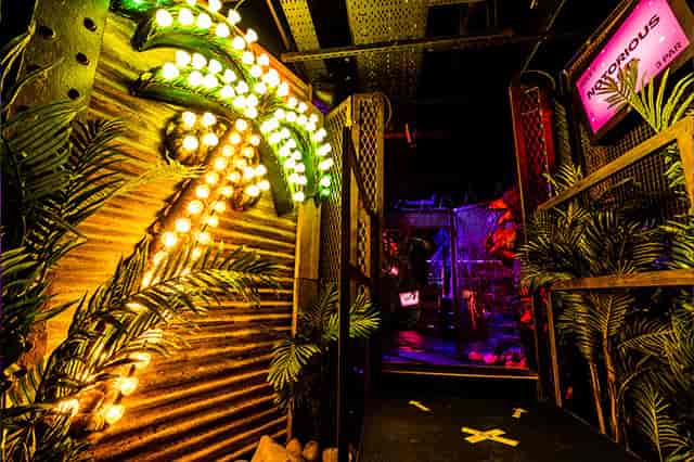 Vibrant entrance with neon palm trees at Junkyard Golf Club for themed events.