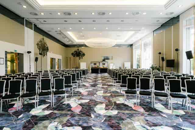 Spacious ballroom in Bogenhausen set for a corporate conference with black chairs.