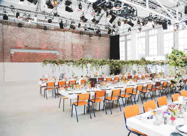 Event space in De Hallen Studio with long tables and floral centerpieces for corporate gatherings.