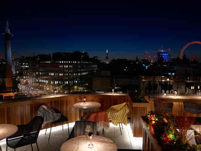 "Christmas party at Trafalgar St James Rooftop with city skyline and warm lighting."