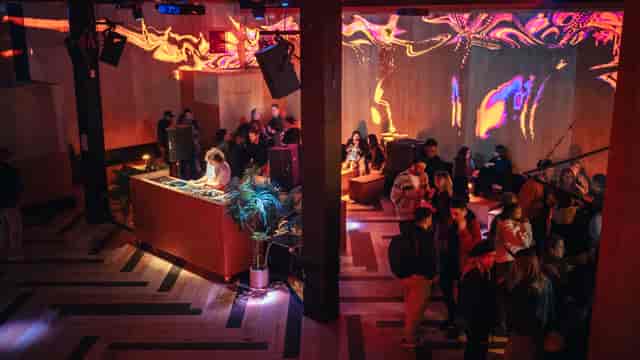 DJ at vibrant Christmas event in Hackney Wick with dynamic lighting and networking.