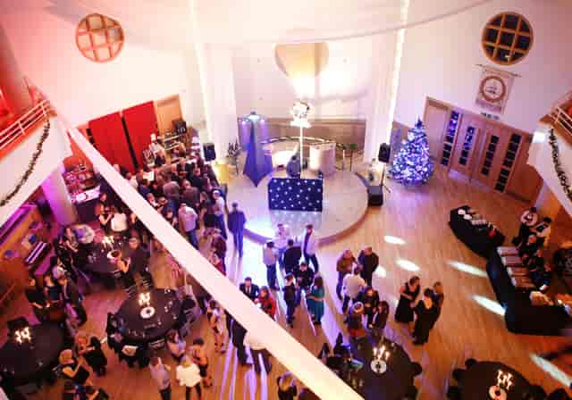 Vibrant event space with round tables and Christmas tree for corporate holiday parties.