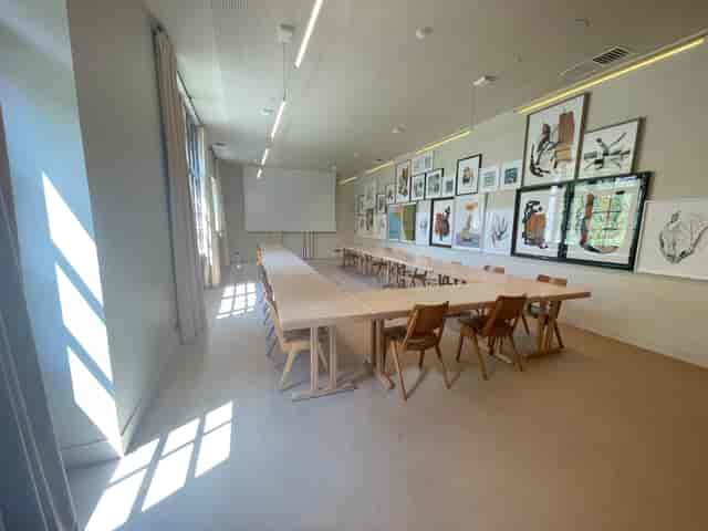 Meeting room l’Aquarelle with wooden table, ideal for workshops and strategic meetings.