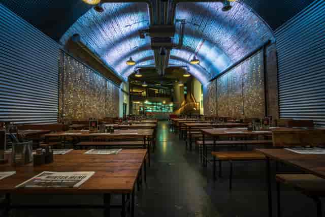 The Old Arch venue in Mamuśka, featuring warm wooden tables for event receptions.
