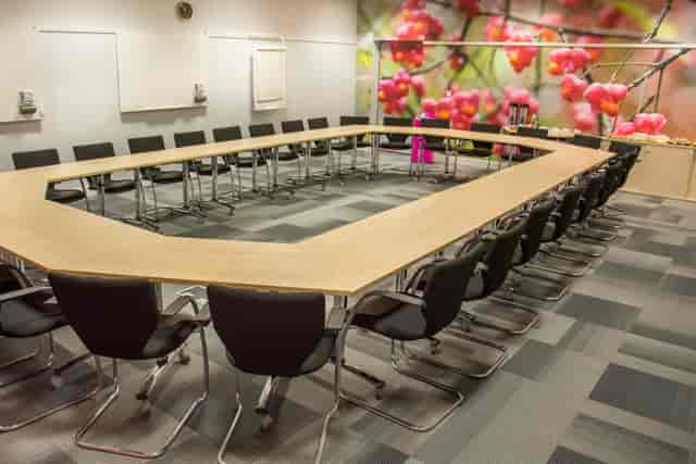 Auditorium meeting room with U-shaped table and floral backdrop for workshops.