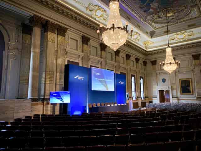 Historic ballroom conference: blue stage, tiered seating.
