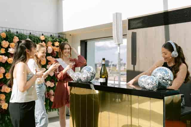 Vibrant event setup at Met Lounge with stylish bar, DJ, and floral backdrop.