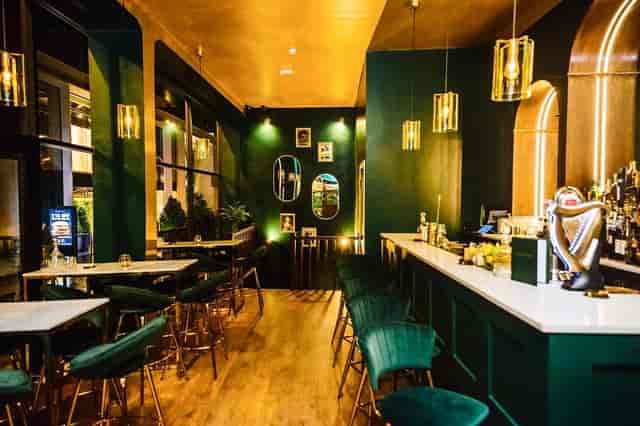 Stylish modern bar with green walls, ideal for networking events and gatherings.