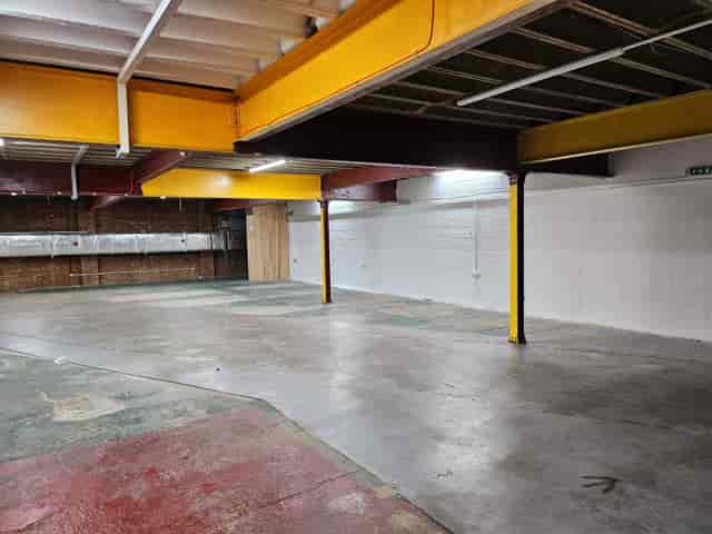 Spacious industrial venue with exposed beams, perfect for workshops and exhibitions.