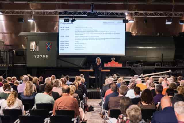 Expo at Spoorweg Museum with vintage train backdrop, engaging conference setting.