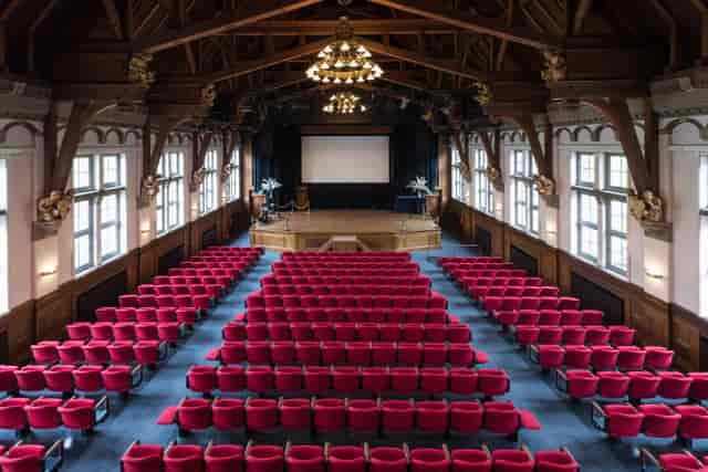 Spacious event venue with red seating and stage at Royal Tropical Institute for conferences.