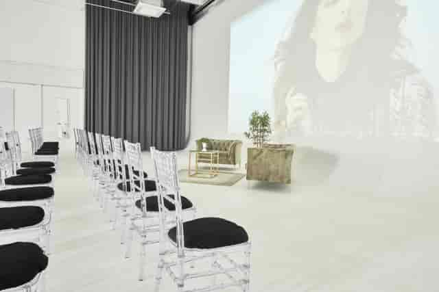 Modern event space with white chairs and projection screen for presentations or gatherings.