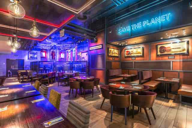 Vibrant Hard Rock Cafe Piccadilly Circus stage with neon "SAVE THE PLANET" sign for events.