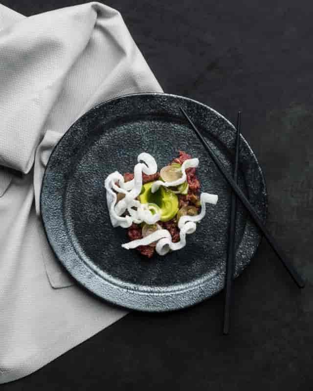 Elegant dish on dark plate at IMA Rooftop Terrace, ideal for corporate gala or upscale wedding.