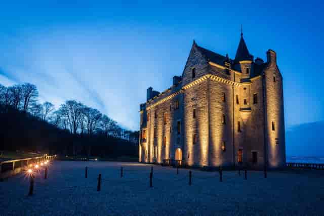 Barnbougle Castle at dusk, illuminated for weddings and events, showcasing elegant architecture.