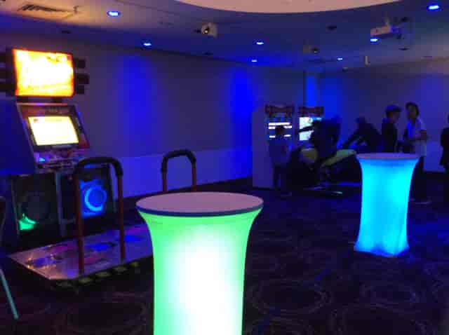 Madison Room at Avenue Banqueting with blue lighting, cocktail tables, and arcade games.