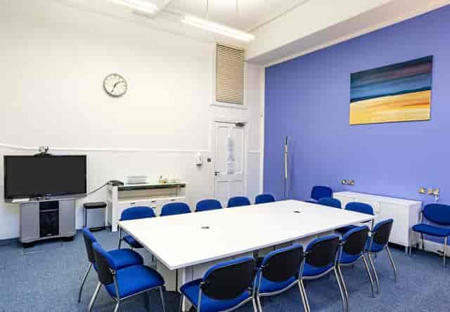 Well-lit meeting room with large white table and blue chairs for productive discussions.