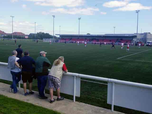 Newtown Roofing and Building Stand at Ainslie Park Stadium during a lively sports event.