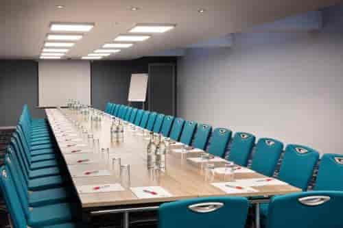 Modern meeting room with turquoise chairs at Leonardo Hotel Heathrow for professional events.