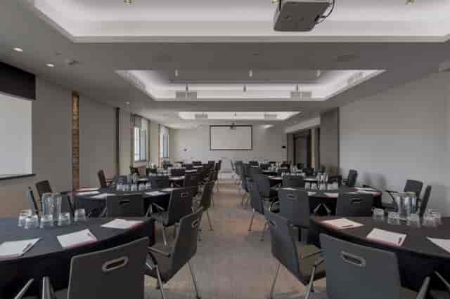 Chancellor Suite at etc.venues County Hall: modern meeting space with round tables for events.