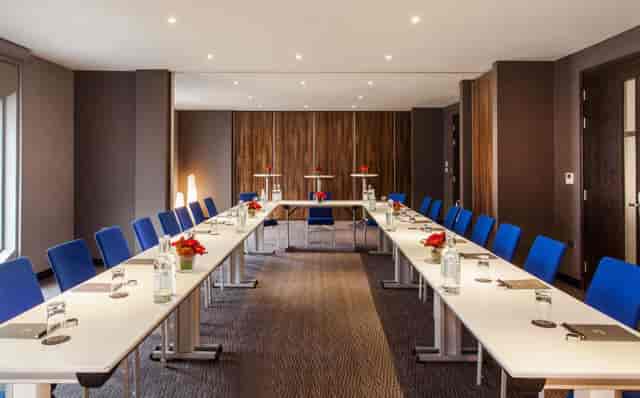 Meeting room with U-shaped tables and bright blue chairs for professional events.