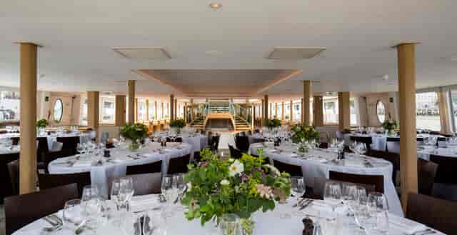 Elegant event space on Silver Sturgeon boat with floral centerpieces for corporate gatherings.