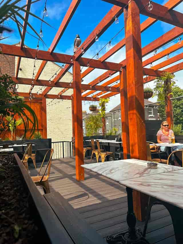 Stylish outdoor lounge with wooden pergola, ideal for networking events and gatherings.