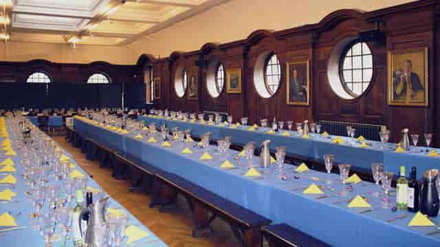 Banquet setup in UCS Venues' Refectory with blue tablecloths and elegant decor.
