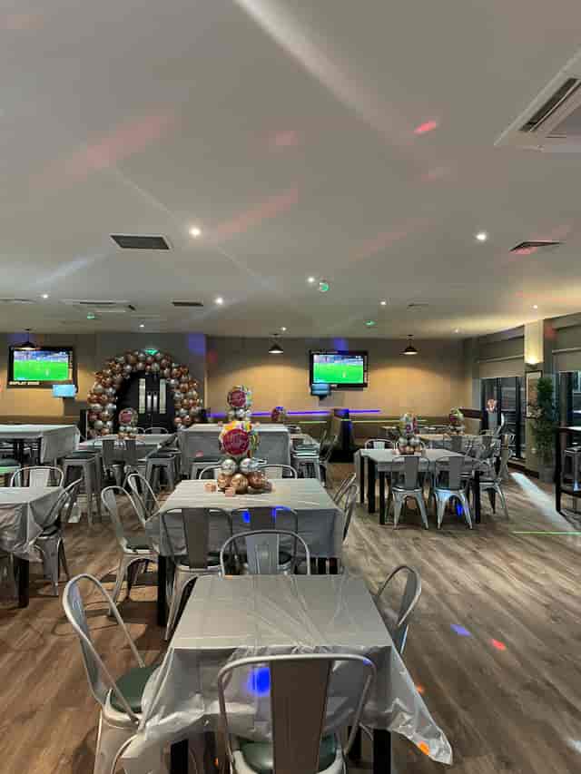Versatile event space in Powerleague Manchester with silver-dressed tables for gatherings.