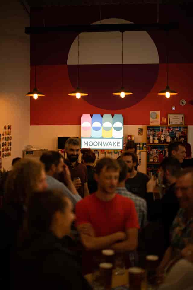 Vibrant networking event at Moonwake Taproom with a lively crowd and colorful branding.