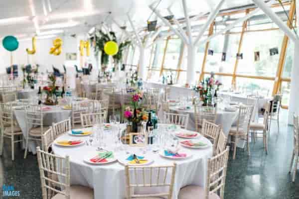 Contemporary glass-walled event space with elegant tables for celebrations and corporate gatherings.