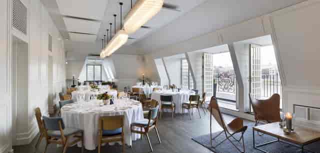 Elegant event space with round tables and natural light for upscale meetings and celebrations.