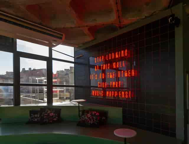 Rooftop meeting space in TOPO Lisboa with neon sign for creative workshops.