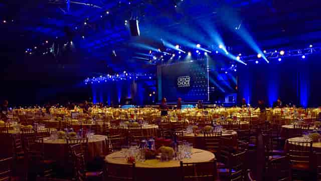 Elegant banquet setup in California's Barker Hangar with gold chairs and blue lighting.