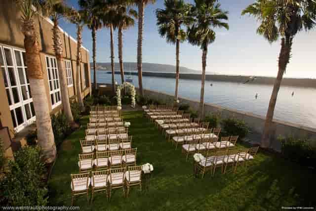 Outdoor wedding venue at Portofino Hotel with lush lawn and waterfront backdrop.
