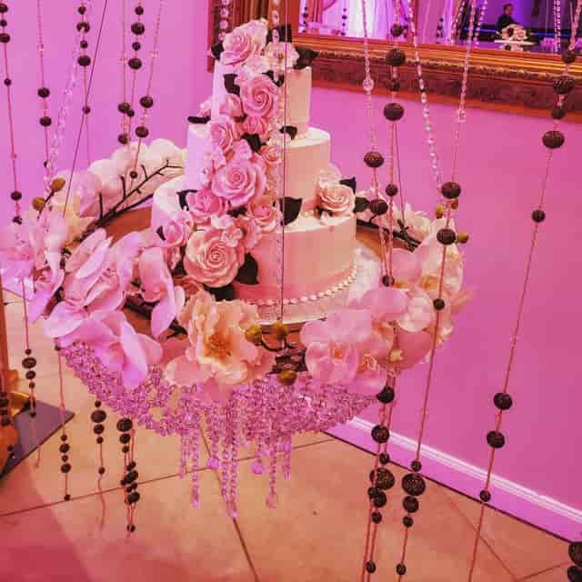 Elegant tiered white cake with pink roses in Mels Fab Events banquet hall for weddings.