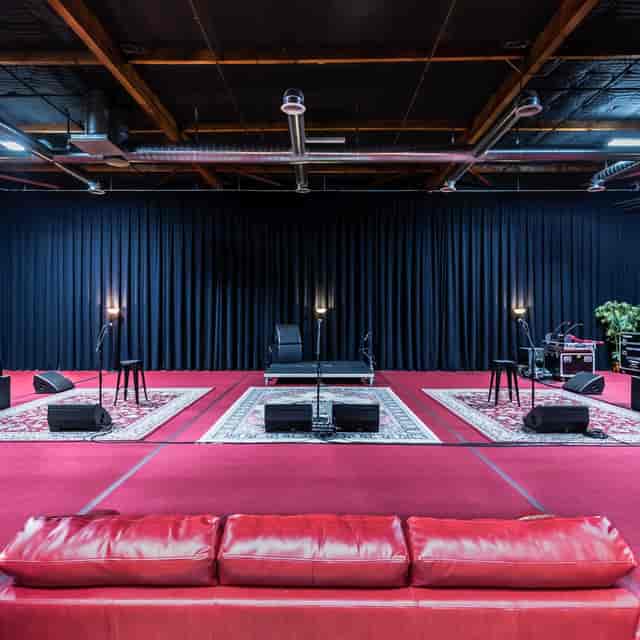 Intimate event stage setup at Francisco Studios LA with black backdrop and lighting.