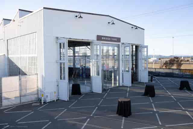 Outdoor courtyard at The Bridge Yard, featuring black tables for events and networking.