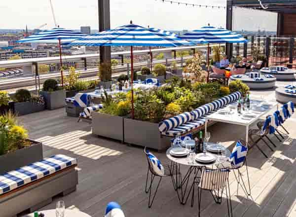 Stylish Skylark Rooftop Bar with blue umbrellas, ideal for events and celebrations.