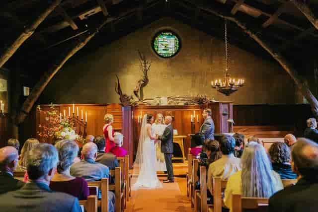 Intimate wedding ceremony in Luscious Garden, Swedenborgian Church with warm lighting.
