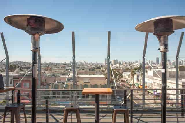 Stylish rooftop patio with heaters and city skyline view, perfect for events and gatherings.